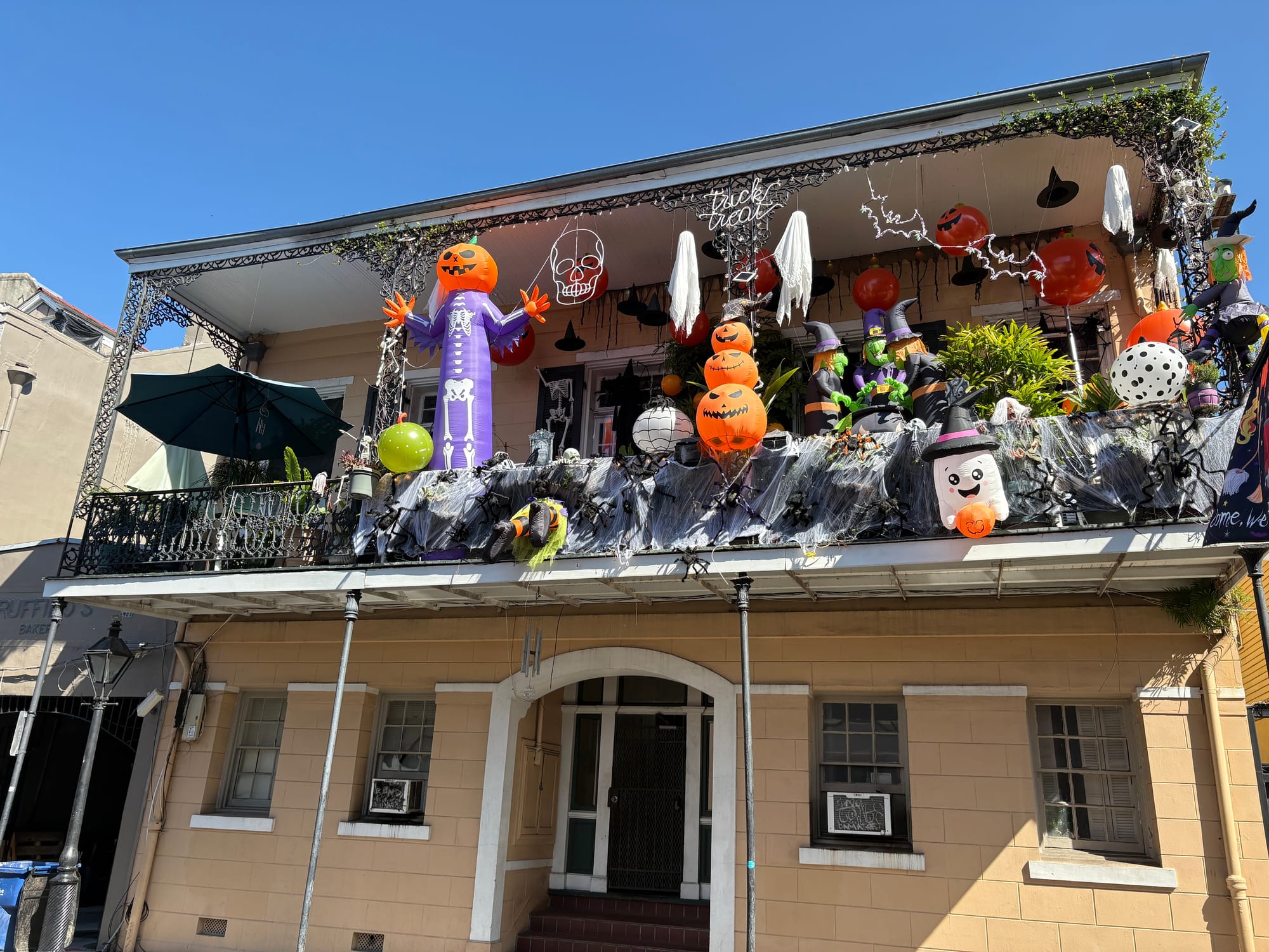 A classic New Orleans French Quarter home, with a gallery full of inflatable halloween decor, sprung with spiderwebs and pumpkin lanterns